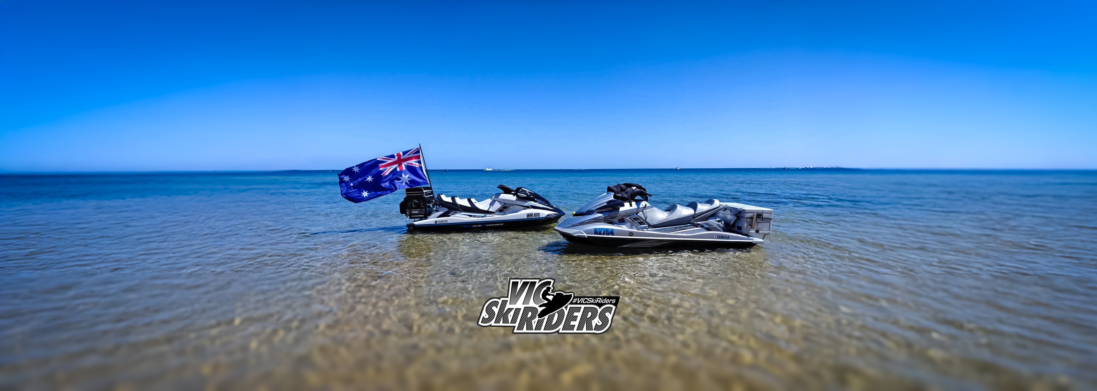 Two Yamaha jet skis parked in shallow water with Australian flag flying on Australia Day