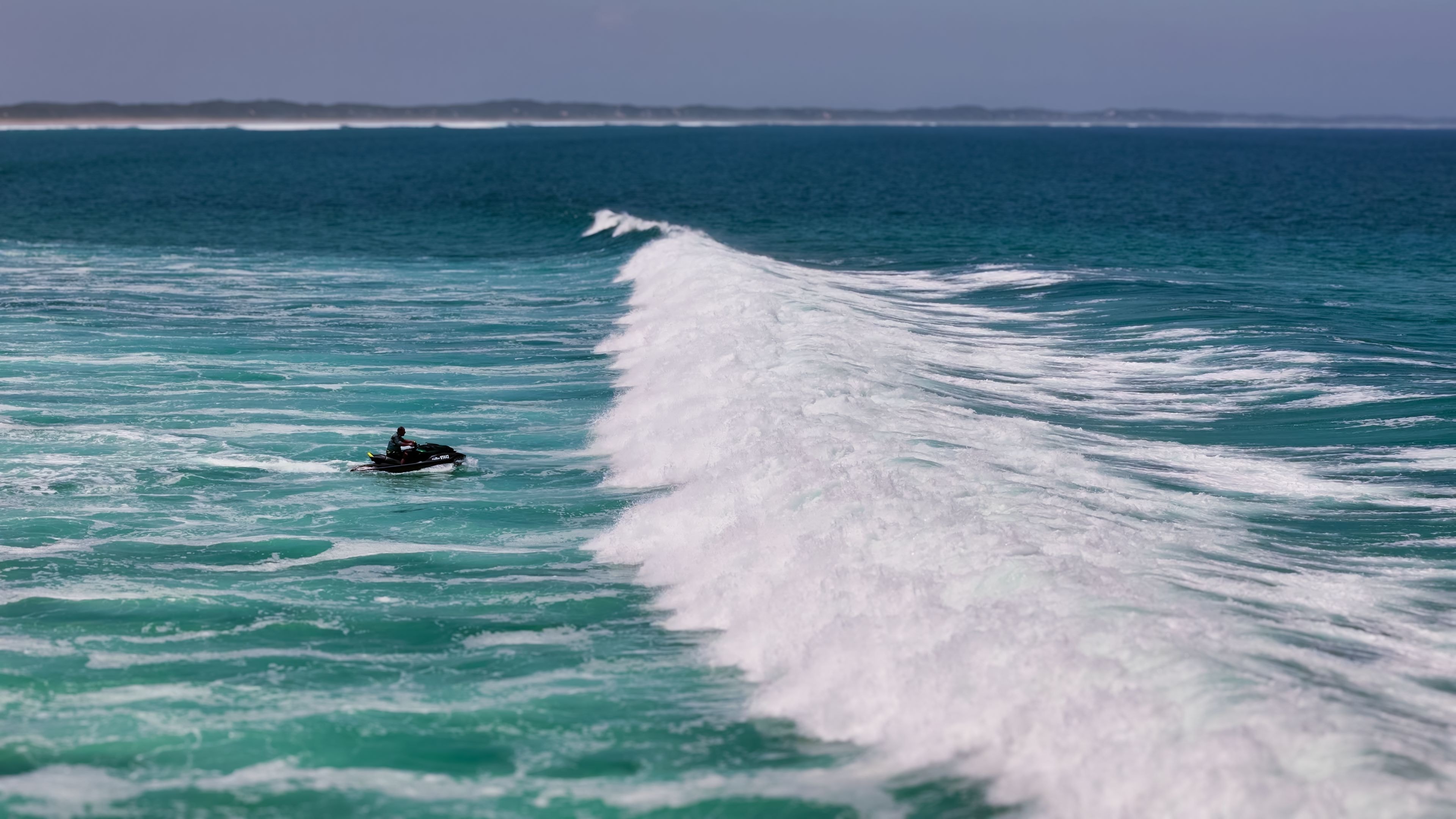 Rider on a black Sea-Doo alongside a massive ocean wake on open water