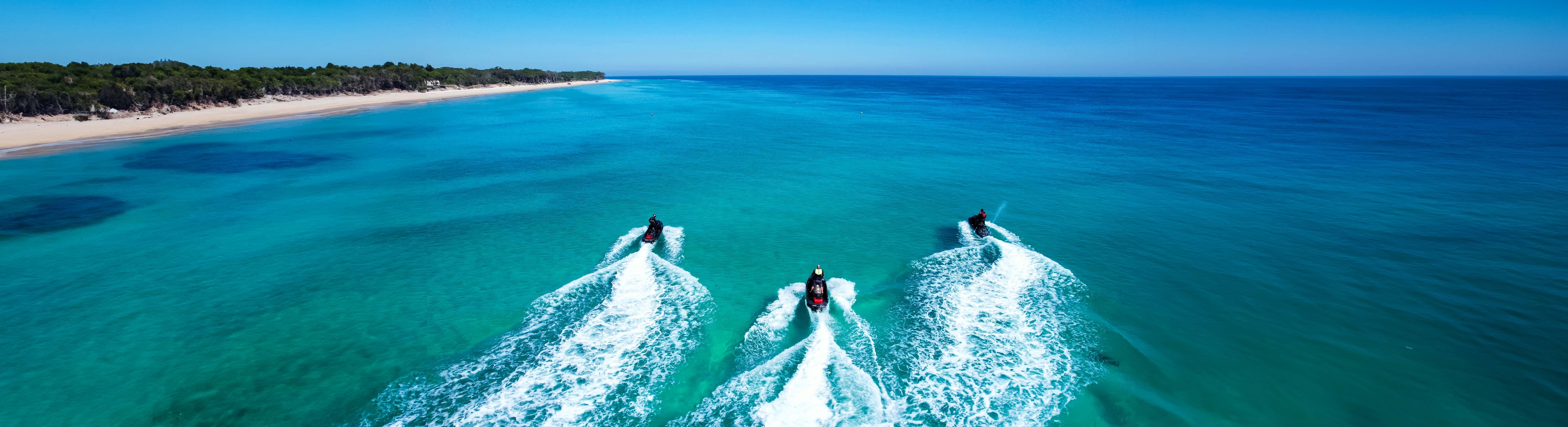 Three jet skis riding in formation at Moreton Island